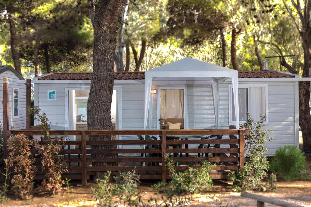 奥尔贝泰洛Giannella Camping的白色小屋,有树和栅栏