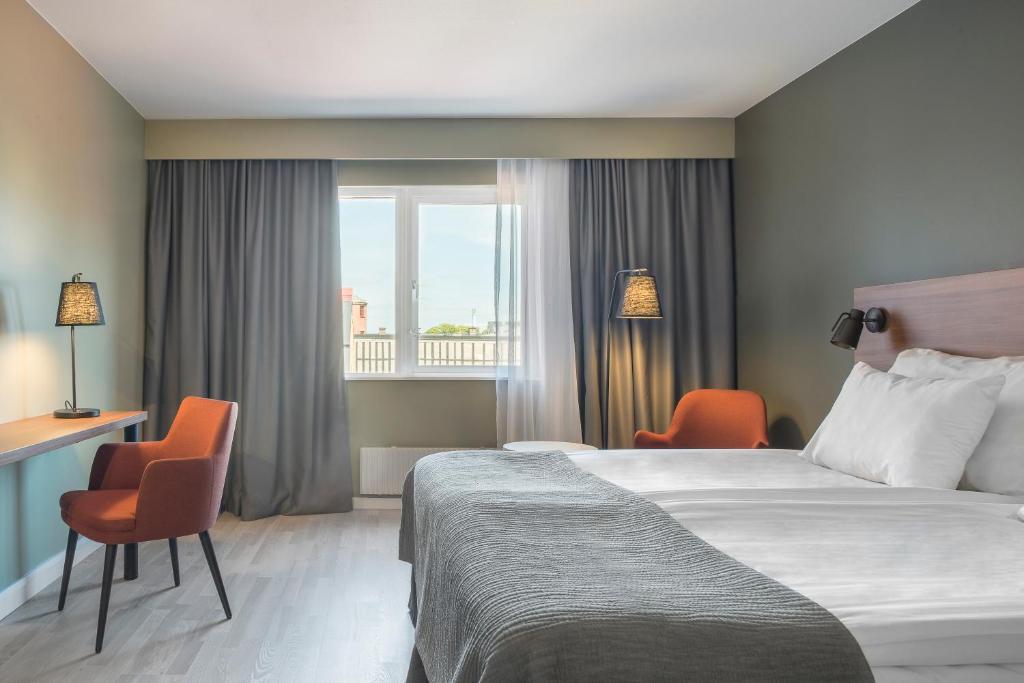 克里斯蒂安斯塔德克里斯蒂安斯塔德品质酒店的酒店客房设有一张床、两把椅子和一扇窗户。