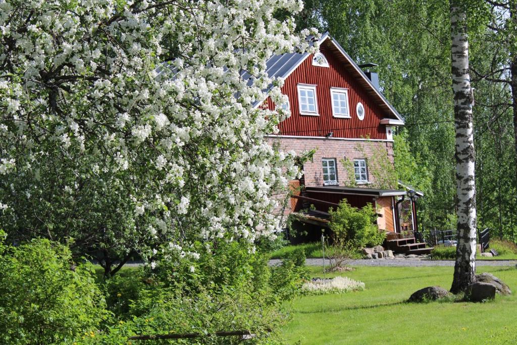 OravasaariNukula Guestrooms的红屋顶的房子和一棵白花树