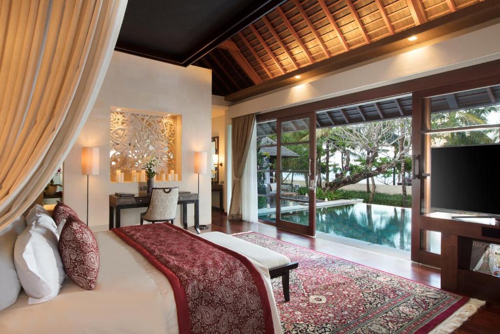 努沙杜瓦皇家珊特瑞安酒店的一间卧室配有一张床、一台电视和一个游泳池