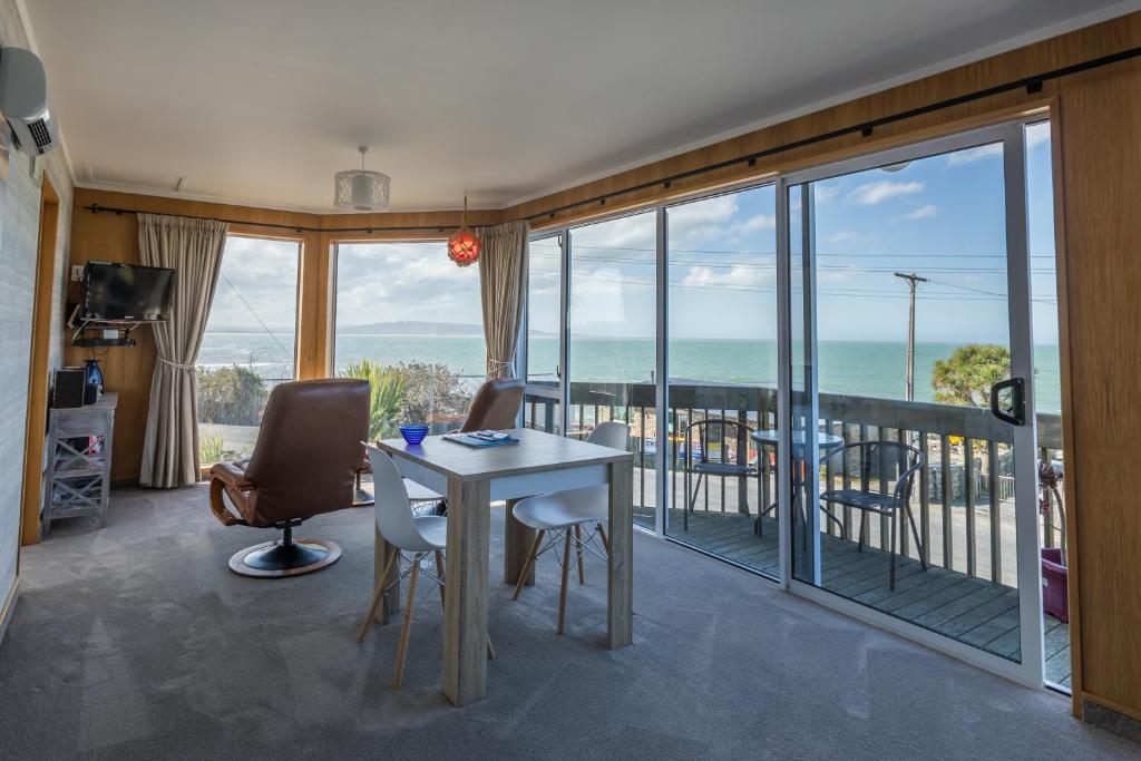 努盖特角Kaka Point Spa Accommodation - Catlins的一间带桌椅的客厅和一个阳台