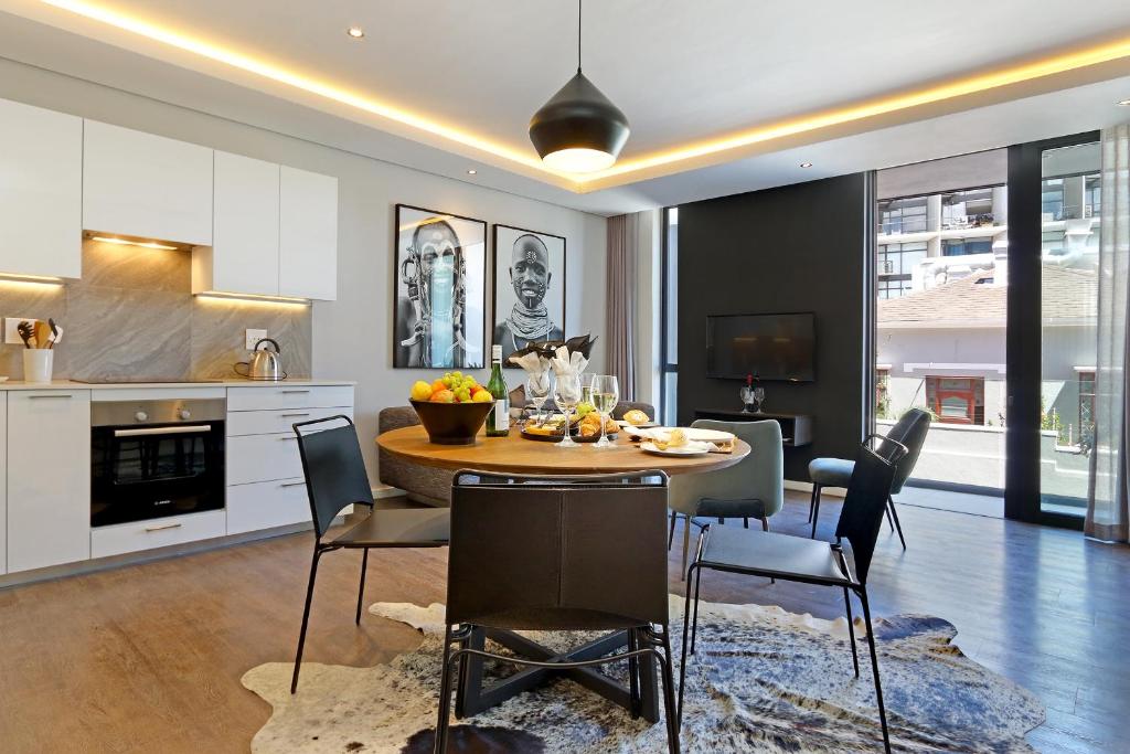 开普敦Chelsea Luxury Suites by Totalstay的厨房以及带桌椅的用餐室。