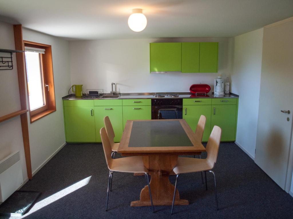 RosswaldChalet Bergfink的厨房配有绿色橱柜和木桌及椅子