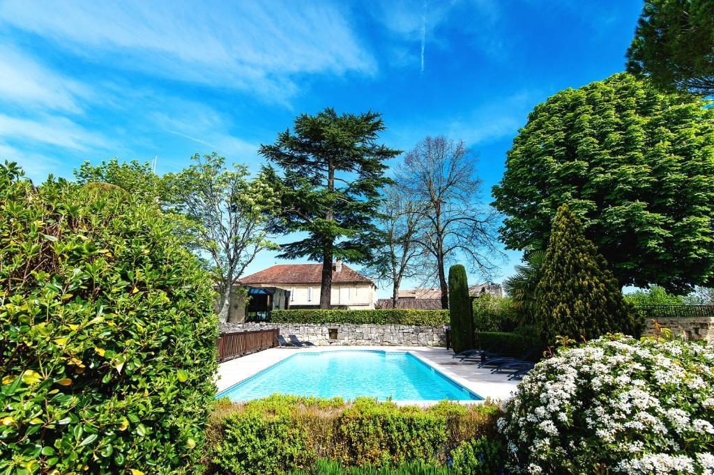 圣艾米隆Hôtel Au Logis des Remparts的灌木花园中的游泳池