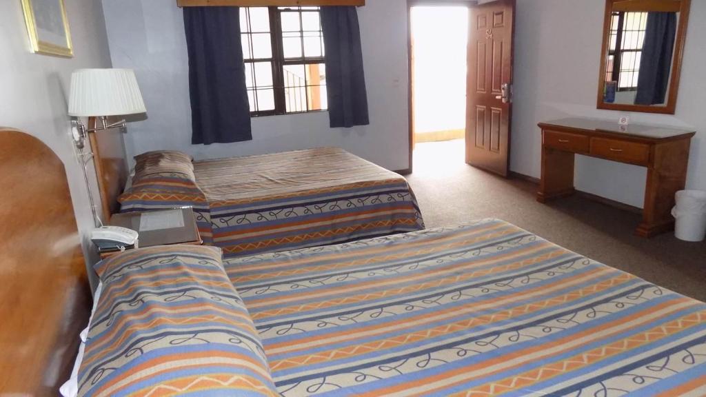 CuauhtémocHotel del Camino的一间卧室设有三张床和一张带台灯的桌子