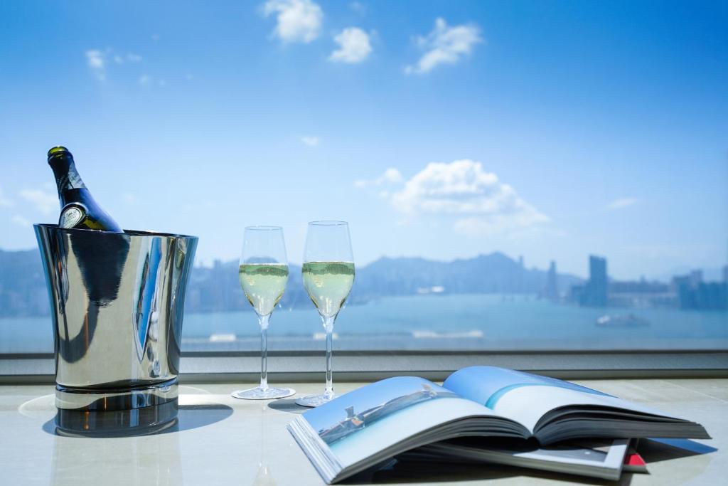 香港悦品海景酒店(观塘)的一张桌子,上面放着两杯葡萄酒和一本开放式的书