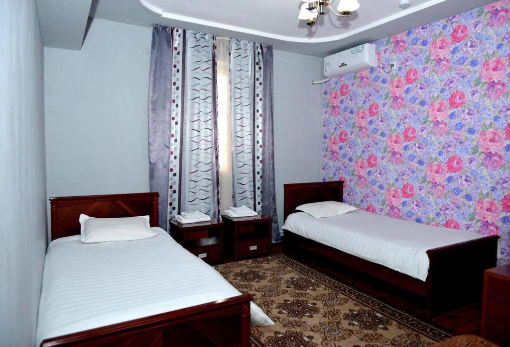 塔什干克拉特酒店的小客房内的两张床,配有花卉壁纸