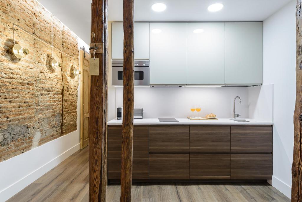 马德里Charming Madrid Center - Estancias Temporales的厨房配有木制橱柜和砖墙
