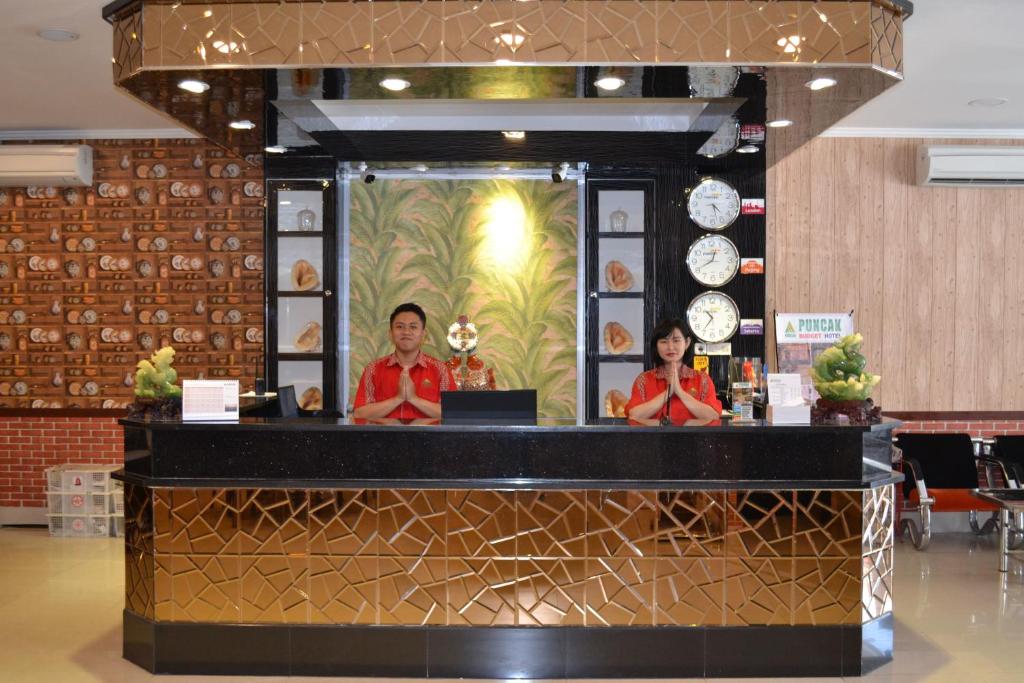 邦加槟港Puncak Budget Hotel的站在餐厅柜台后面的男人和女人