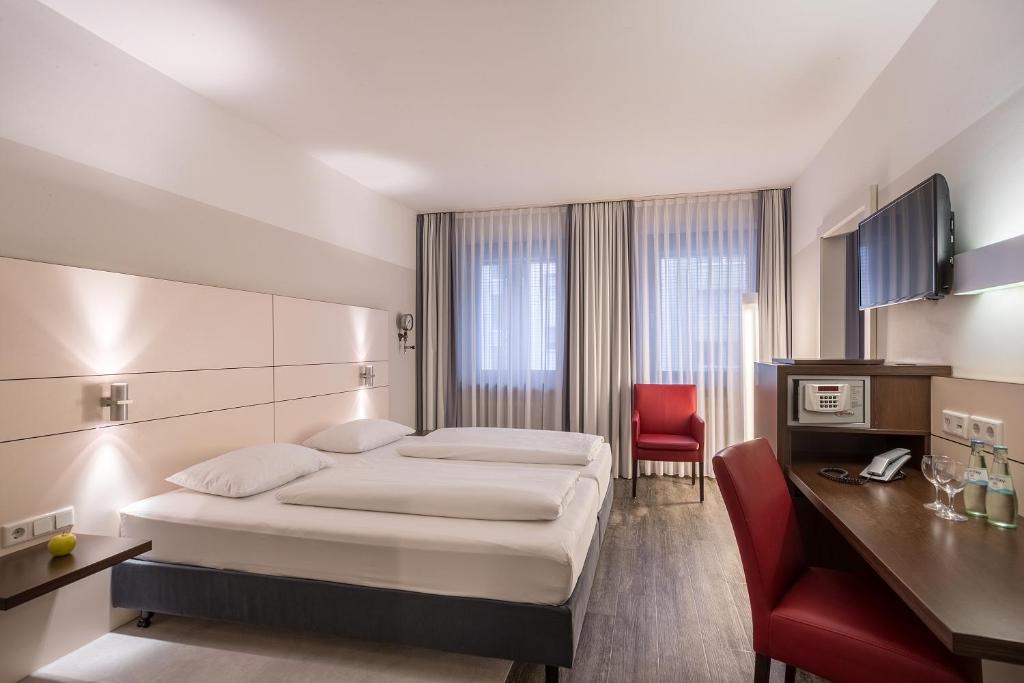 杜伊斯堡弗洛特尔杜伊斯堡索拉塔酒店的酒店客房,配有一张床和一张红色椅子
