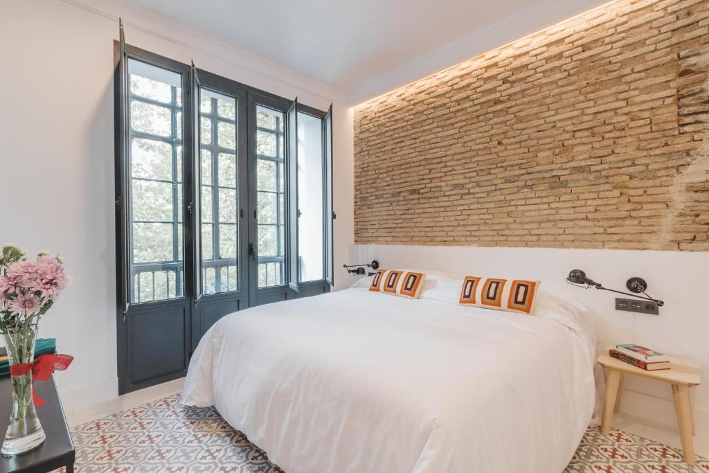 塞维利亚Uma Suites Parada del Marqués的卧室配有白色的床和砖墙