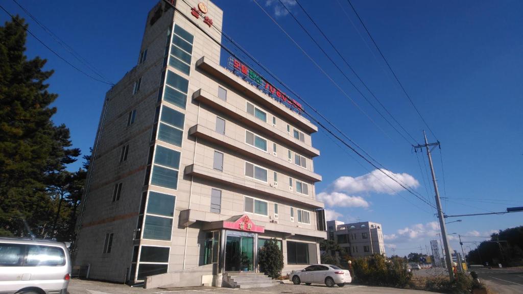 襄阳郡Seolhwa Motel的一座高大的建筑,前面有一辆汽车