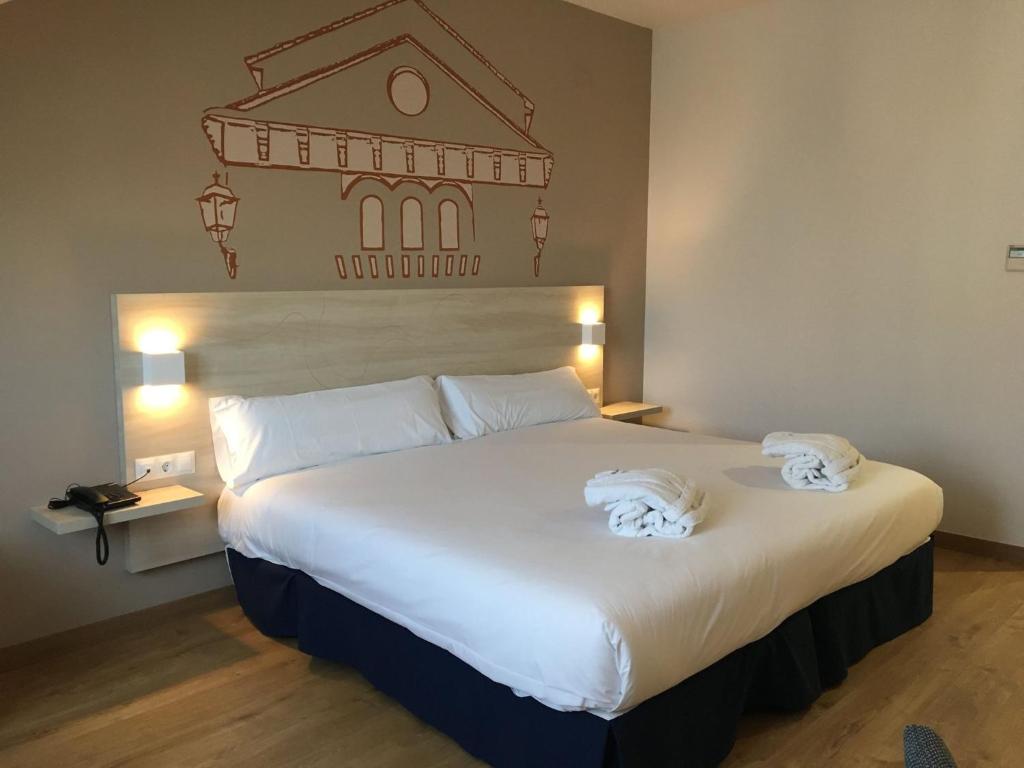 GraenaHotel Balneario de Graena的卧室配有带毛巾的大型白色床