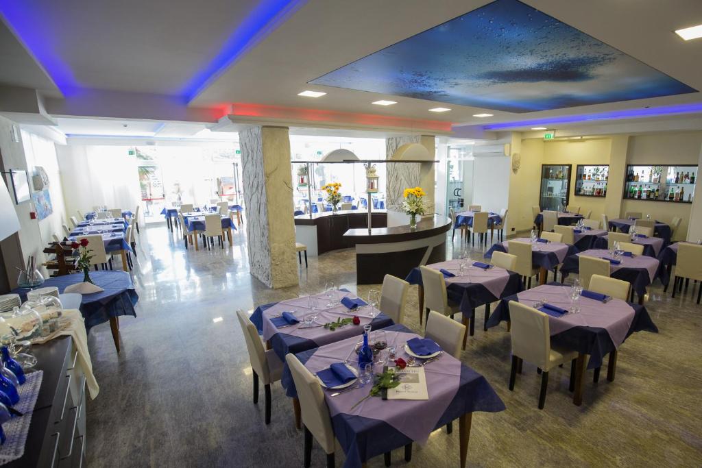 马里纳迪马萨鲁马酒店的一间配备有桌椅及蓝餐巾的用餐室