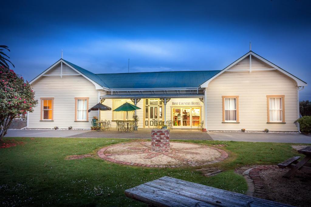 KarameaKaramea Village Hotel的前面有长凳的大白色房子