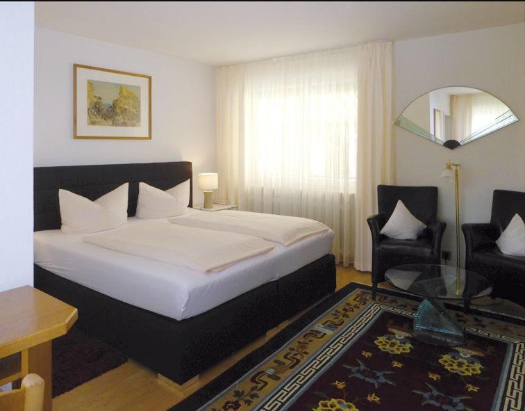 巴特克罗青根霍夫曼祖尔姆乐酒店的一间卧室配有一张床、一把椅子和一张桌子