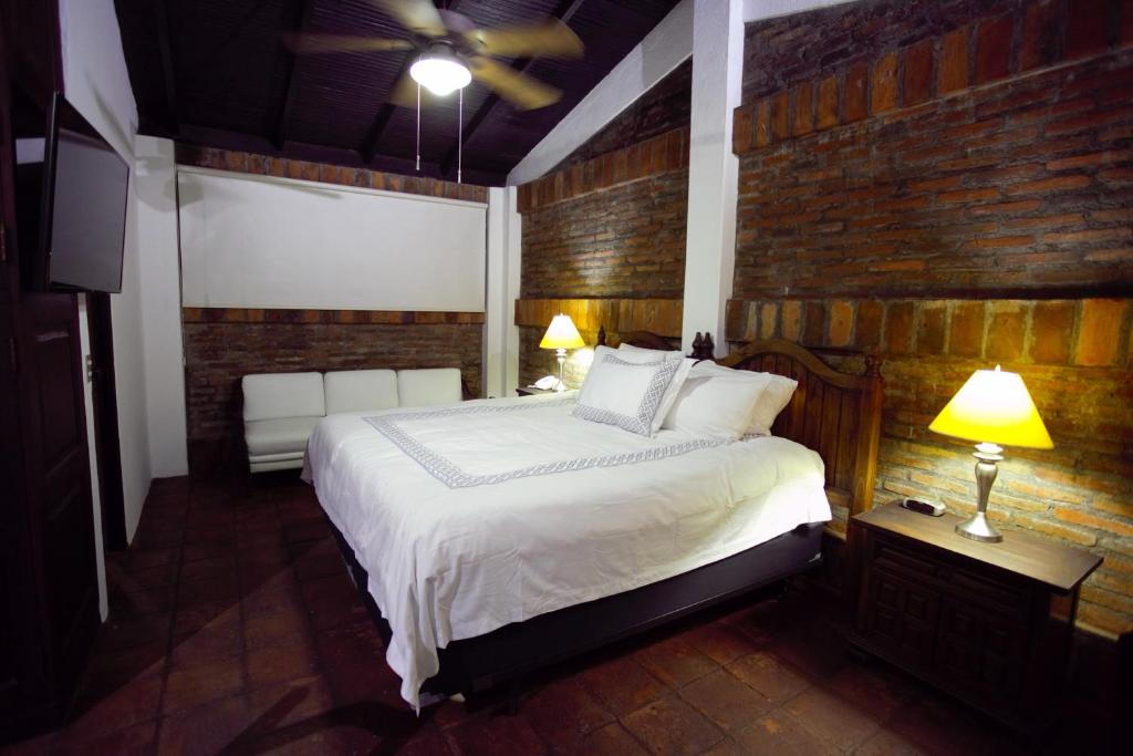 马那瓜卡萨科洛尼尔精品酒店的一间卧室设有一张床和砖墙