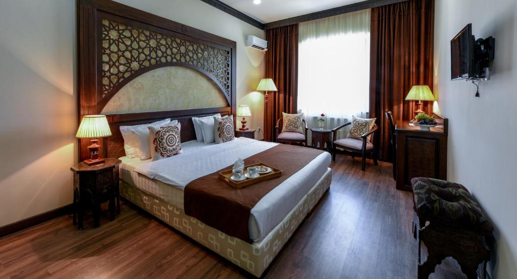 撒马尔罕东方之星酒店的酒店客房设有一张大床和一张桌子。