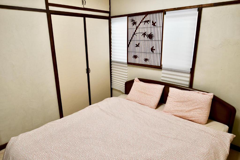 东京花庵旅舍的一间卧室配有带粉红色枕头的床和窗户。