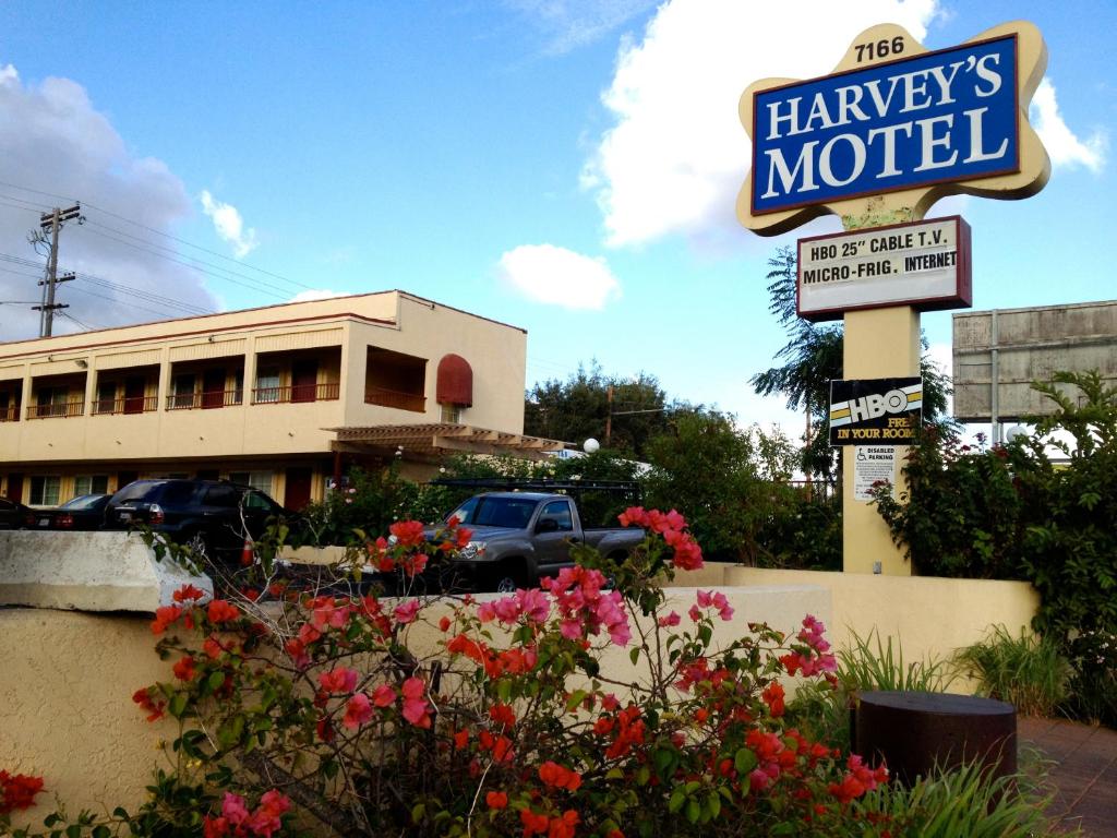 圣地亚哥Harvey's Motel SDSU La Mesa San Diego的一座建筑前有鲜花的汽车旅馆的标志