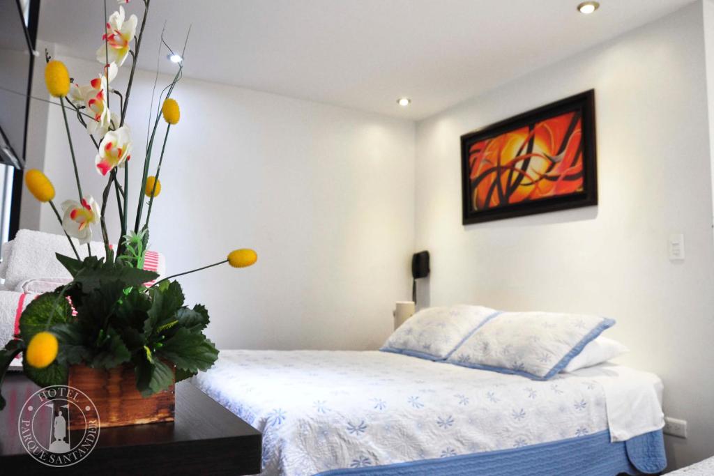 通哈Hotel Parque Santander Tunja的卧室配有一张床,墙上挂有绘画作品