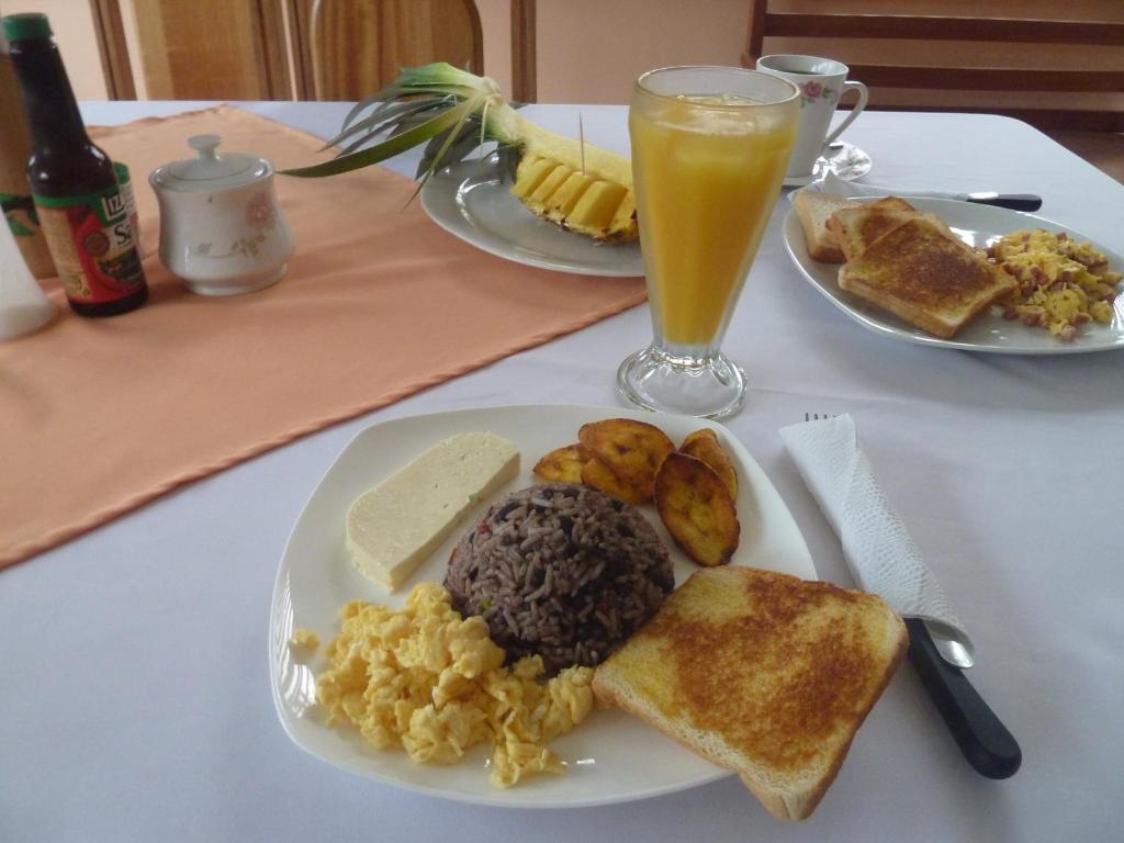 Rio CelestePosada Rural Río Celeste的一张桌子,上面放着两盘早餐食品和一杯橙汁