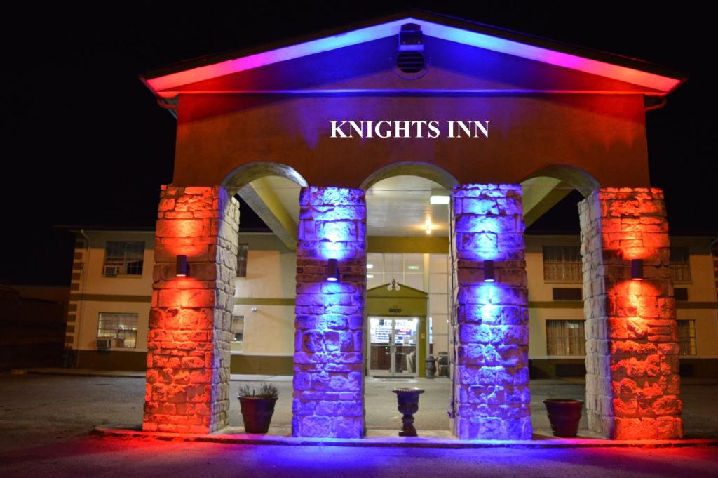 格林维尔Knights Inn Greenville的前面有紫色和蓝色的灯光的建筑