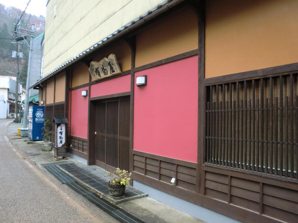 会津若松东山温泉元汤有马屋日式旅馆的街道边有粉红色油漆的建筑