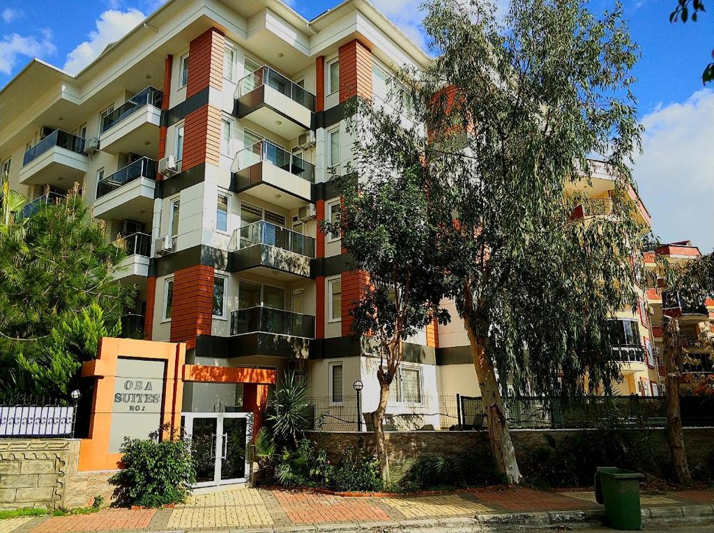 阿拉尼亚Oba Suites Apartmani的一座大型公寓楼,前面有一棵树