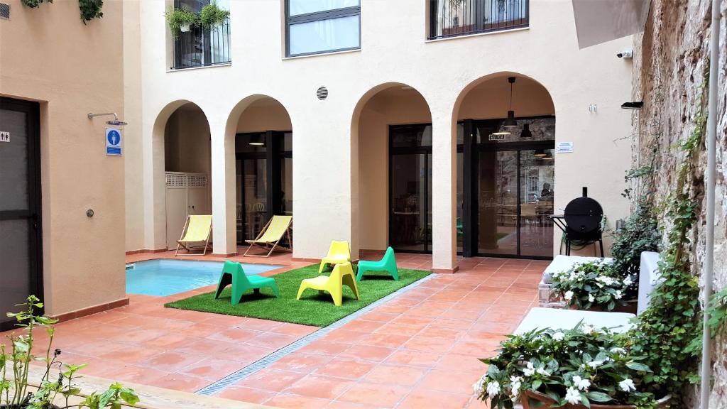 巴塞罗那腾图古旅馆的庭院设有绿色和黄色的椅子和游泳池
