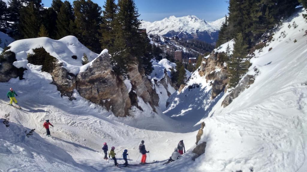 普拉涅贝勒科特Plagne Bellecote Apartments的一群人沿着雪覆盖的山滑雪