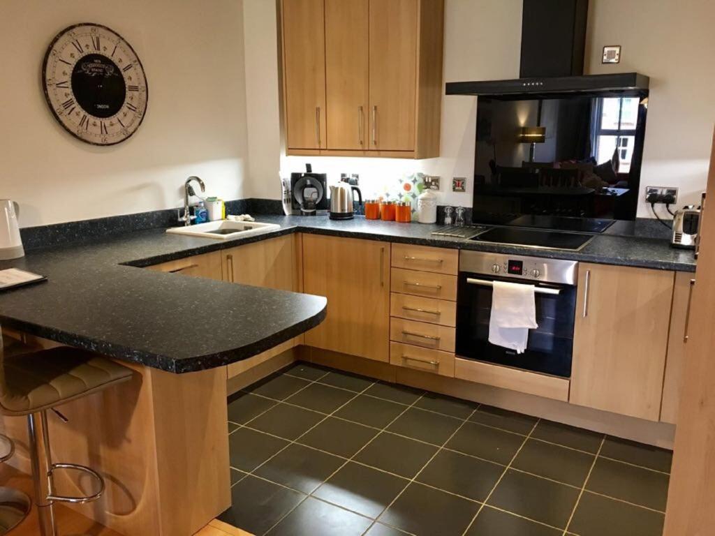 约克Central York Apartment - Skeldergate YO1的厨房配有木制橱柜和黑色台面