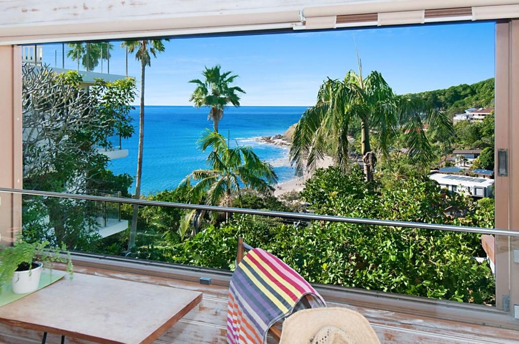 拜伦湾WategosRent的阳台享有大海和棕榈树的景致。