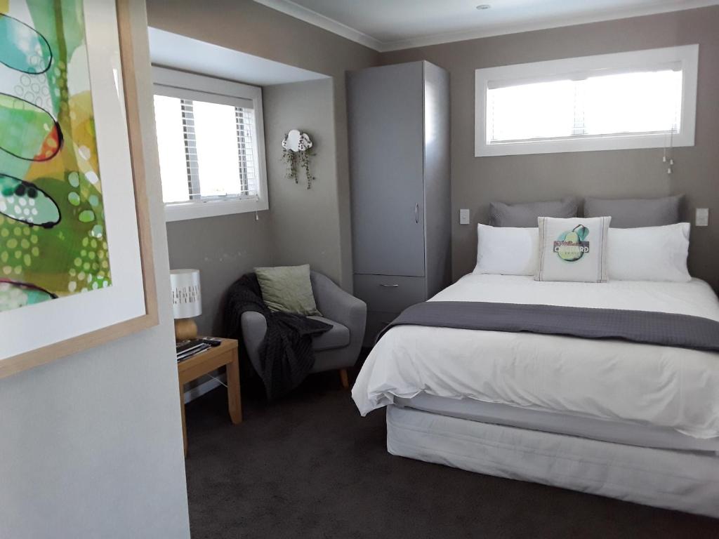 陶波Suite Petite的一间卧室配有一张床和一把椅子,还有两个窗户
