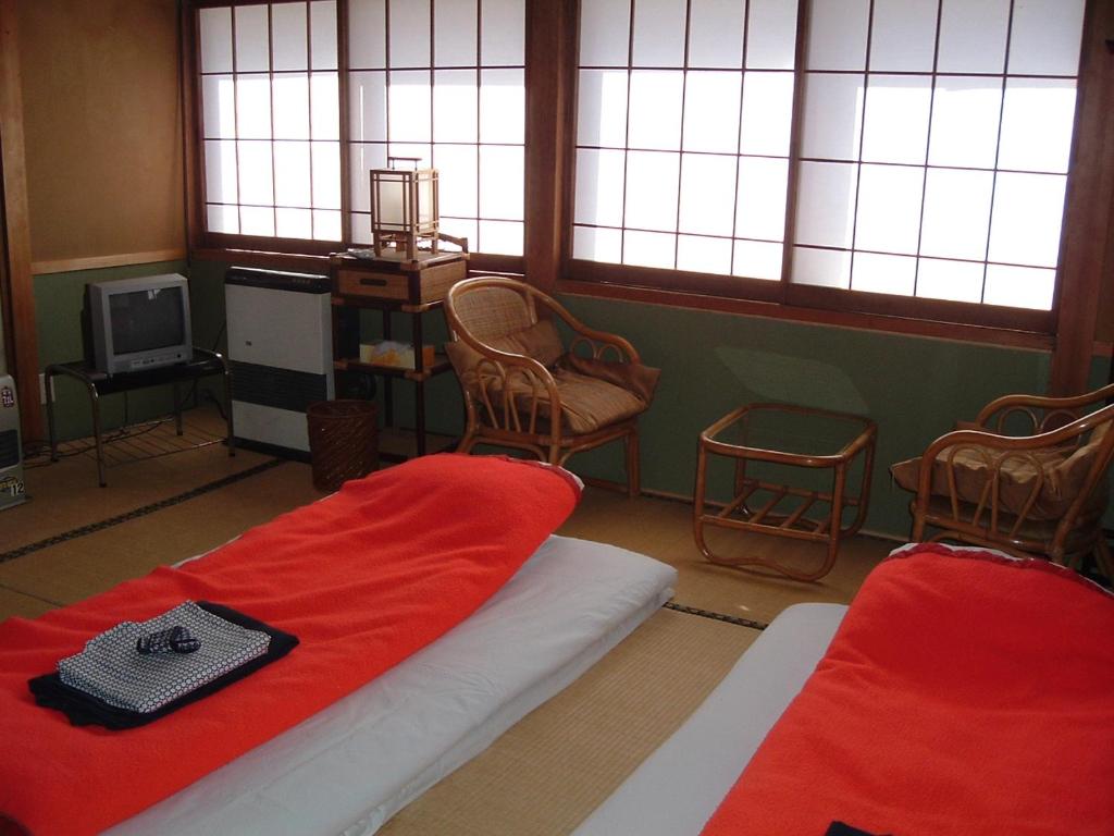 松本36号温泉酒店的客房设有两张床、椅子和窗户。