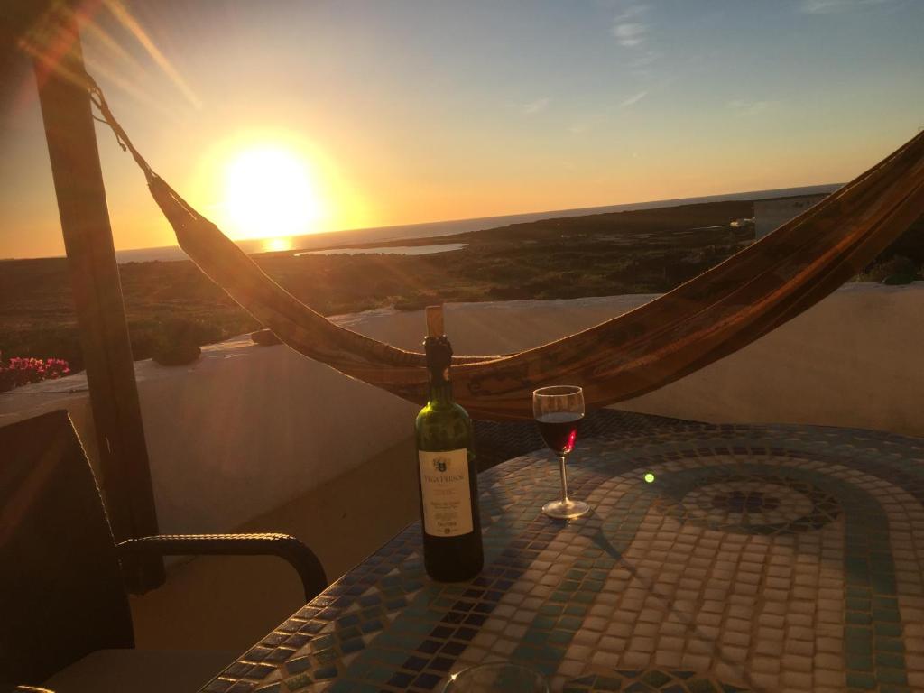 亚伊萨"Ziegenstall" mit Meerblick的一瓶葡萄酒和一杯茶,在餐桌上欣赏日落美景