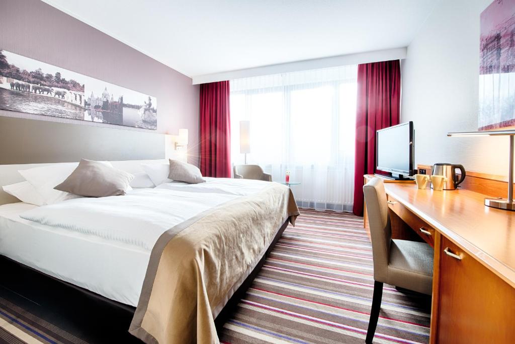 汉诺威汉诺威莱昂纳多酒店的配有一张床和一张书桌的酒店客房