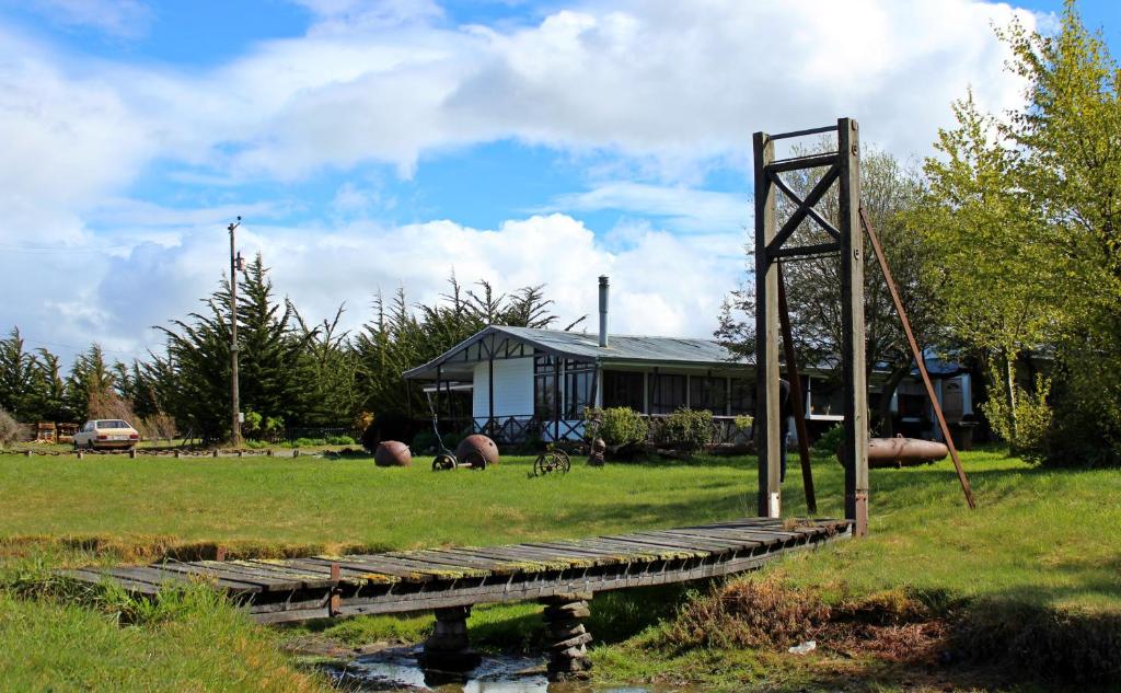 蓬塔阿雷纳斯Hospedaje Isla Magdalena的一座桥,在一座房子前面的池塘上