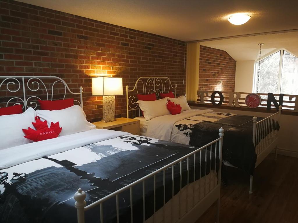 多伦多玛吉联排别墅套房的一间卧室设有两张床和砖墙