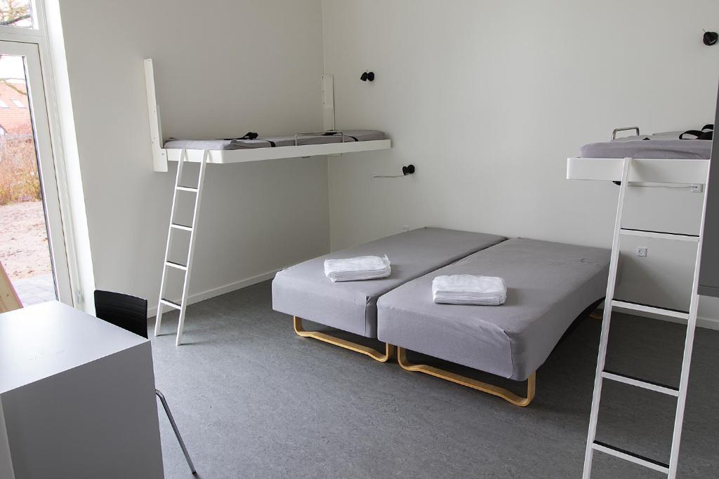 布伦讷斯莱乌Hostel Brønderslev的一间带床和两张双层床的客房以及梯子