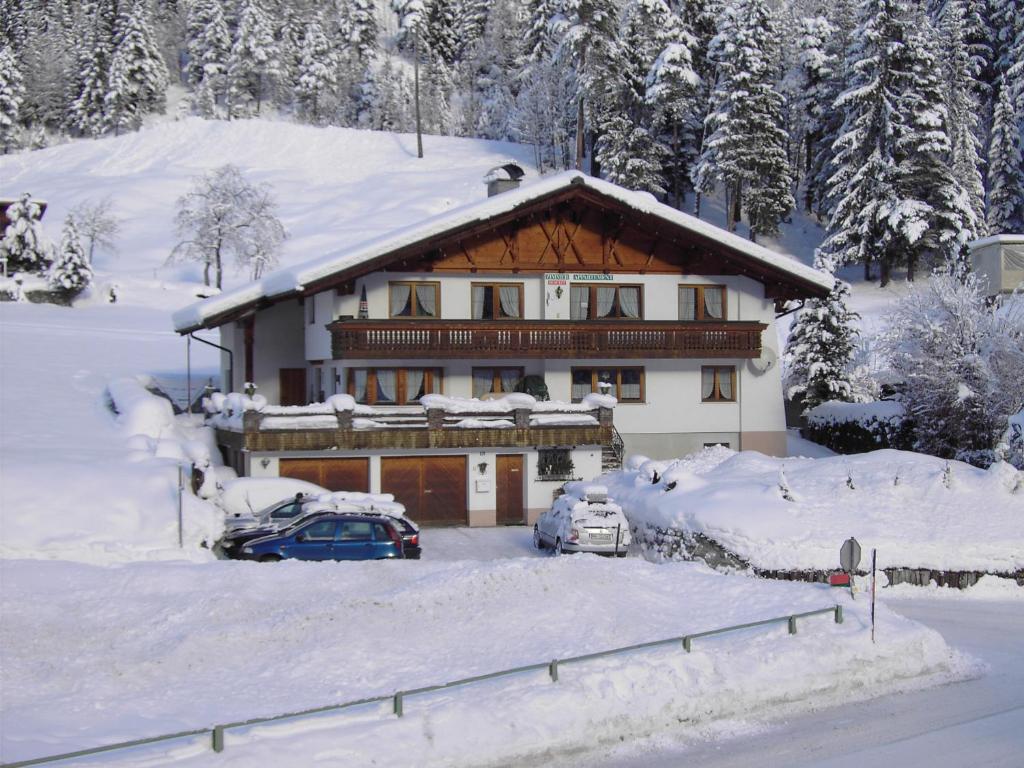 瓦尔德阿尔贝格Pension Seeberger的一座雪覆盖的房子,前面停有汽车