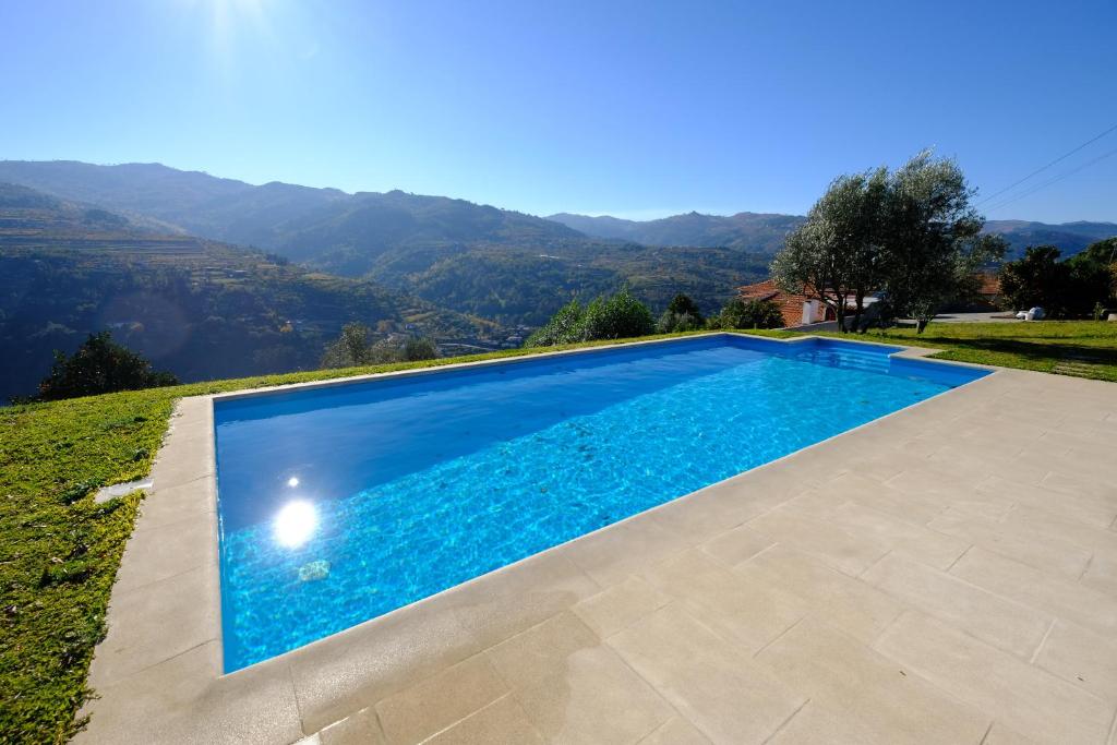 拜昂Casas do Casinhoto - Casa com Vista Douro的一座位于别墅内的游泳池,别墅的背景是群山