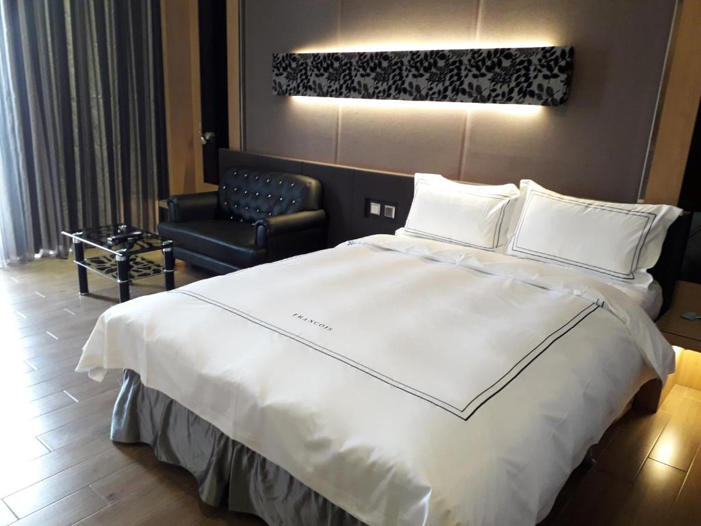 Tuku云林商务旅馆的卧室配有一张白色大床和一把椅子