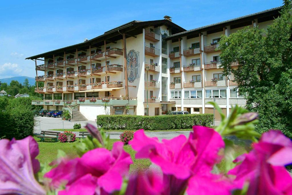 法克湖畔埃格Hotel Kanz的一座大建筑前面有粉红色的花朵
