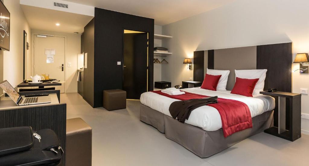 巴黎巴黎十七区奥德利城公寓式酒店的一间卧室配有一张带红色枕头的大床