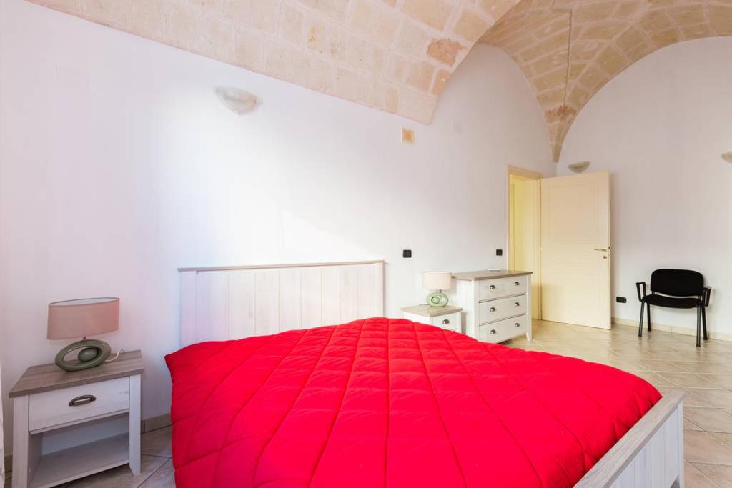 圣维托诺曼Casa Sardelli的一间卧室配有红色的床、一张桌子和一把椅子