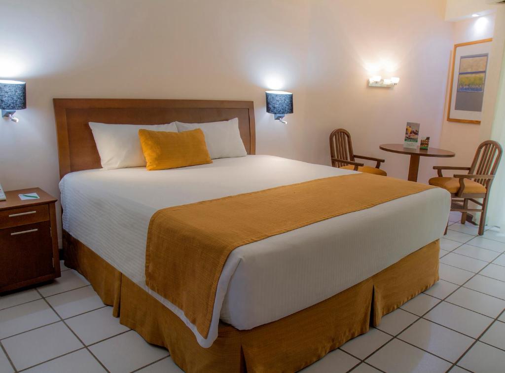比亚埃尔莫萨维瓦维拉尔莫萨酒店的一间卧室配有一张大床和一张桌子及椅子