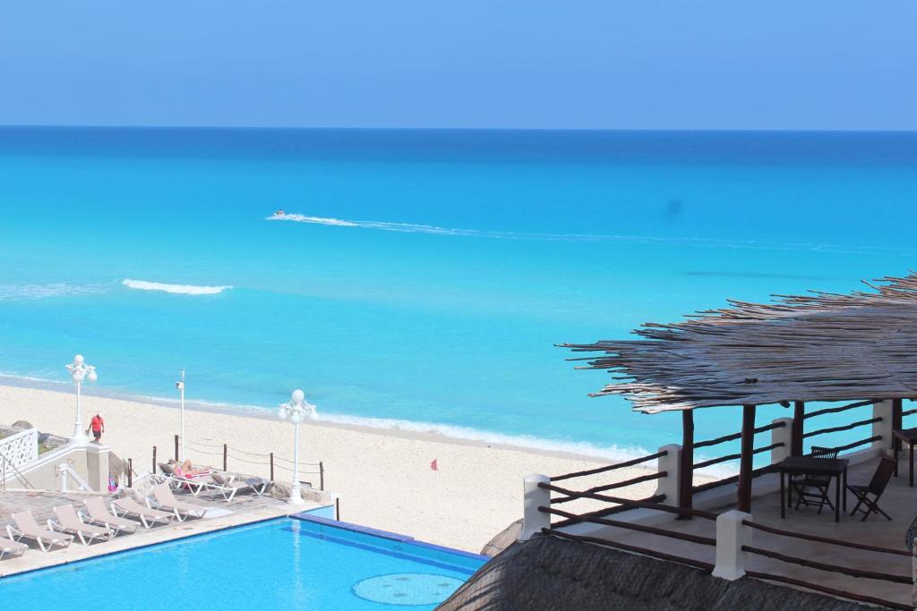 坎昆Cancun Plaza - Best Beach的海滩旁的游泳池配有椅子和遮阳伞
