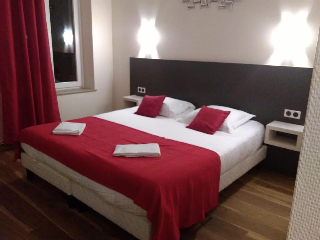 EuvilleLogis Le Provençal的一间卧室配有一张大床,提供红色的床单和毛巾。