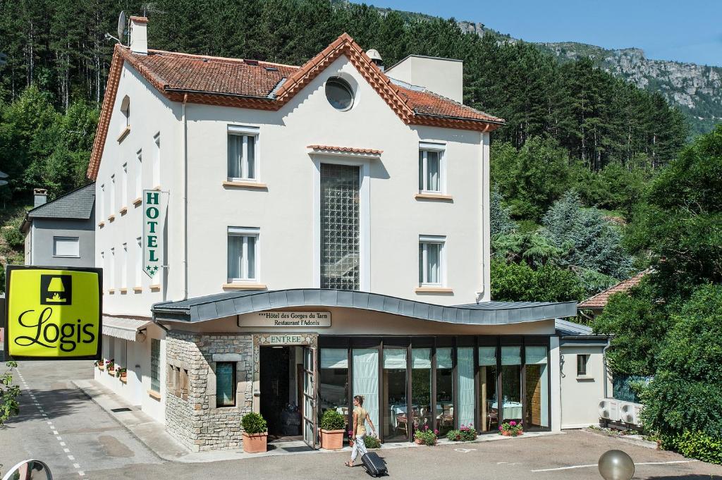 弗洛拉克Logis Hotel Restaurant des Gorges du Tarn的站在建筑物前走的女人